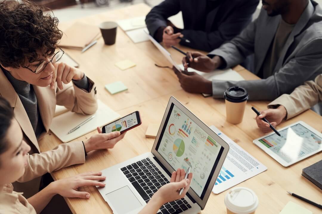 Pessoas à mesa, trabalhando com seus notebooks e papéis